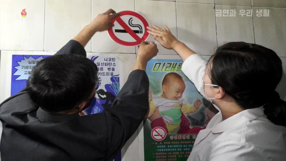 Workers of an antismoking clinic in North Korea put up antitobacco stickers on a building wall, as seen on footage from Korean Central Television. The country is conducting various antismoking campaigns to curb rampant tobacco use especially among its male population. [YONHAP]