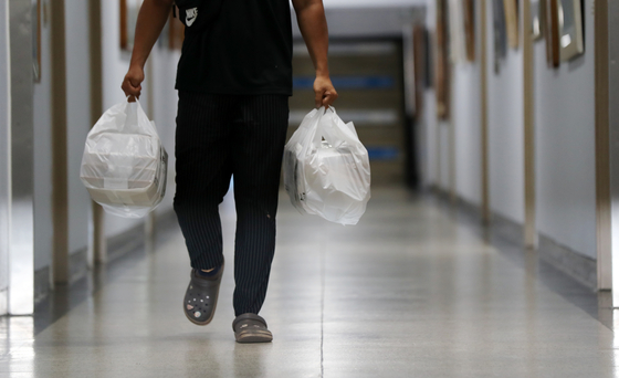 A delivery worker carries food across the Gwangju District Government Office on Aug. 31. Food delivery has increased substantially since the beginning of this year. [YONHAP]