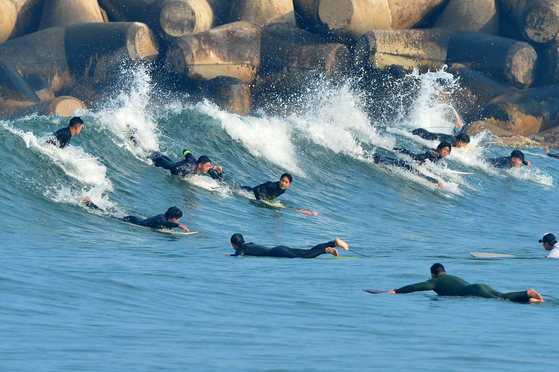 Surfers ride waves off Pohang, North Gyeongsang, on Tuesday, as daytime temperatures hover around 19 degrees Celsius (66.2 degrees Fahrenheit). [NEWS1]