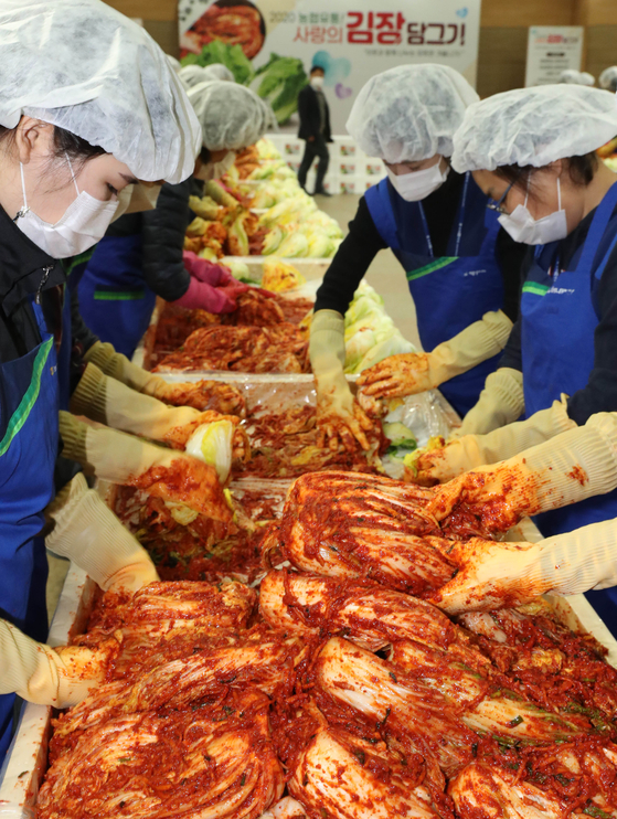 Employees of Nonghyup Hanaro Mart make kimchi at the retailer’s Yangjae branch in southern Seoul on Wednesday during kimjang, a kimchi-making season that usually takes place before the official arrival of winter. [YONHAP]