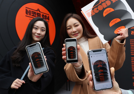 Models pose with LPs and their mobile devices to explain how to view the exhibition online. Hosted by the Ministry of Culture, Sports and Tourism and organized by the Korea Craft & Design Foundation, the exhibition illustrates the history of LP in Korea, and how it grew to have artistic value beyond an analog sound storage medium. [ILGAN SPORTS]