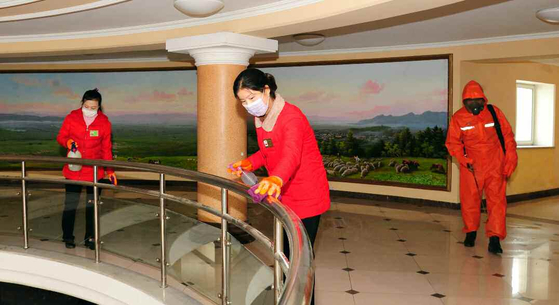 North Korean workers disinfect a government building in Kangwon Province, in a state media photograph. The regime on Wednesday said it elevated its social distancing scheme to the highest level. [NEWS1]