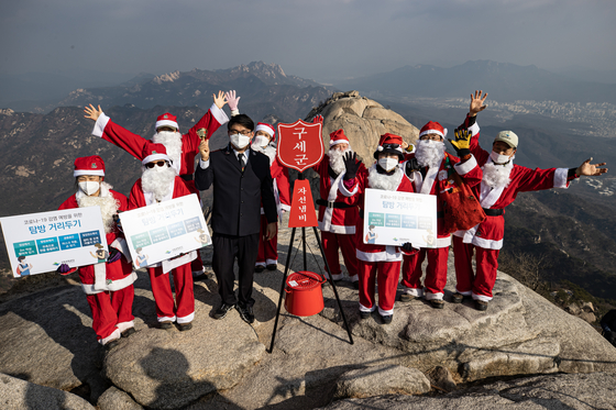 Officials from the Salvation Army in Santa Claus costumes hold a kickoff ceremony to start the annual year-end fundraising campaign on a peak of Mount Bukhan in Seoul on Sunday. [YONHAP]