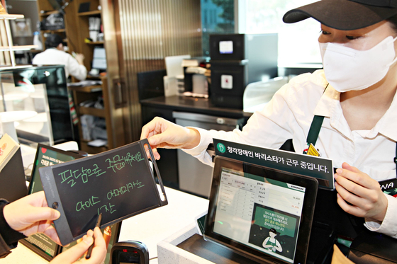 An employee from Starbucks Korea receives an order from a customer who orders an Iced Americano through an electronic notepad. [STARBUCKS KOREA]