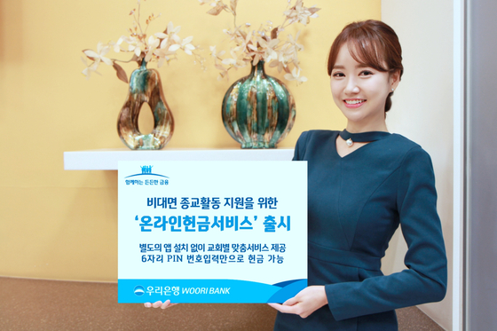 A staffer uses a signboard to explain a service launched by Woori Bank that helps people transfer money to churches via smartphones. [WOORI BANK] 