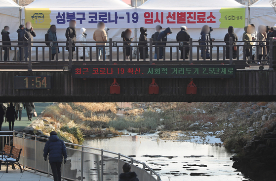 People wait to get tested at a Covid-19 testing site in Seongbuk District, northern Seoul, Friday. [YONHAP]