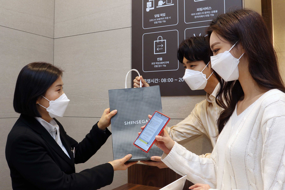 Customers pick up an order they placed online at Shinsegae Department Store’s main branch in central Seoul. [SHINSEGAE DEPARTMENT STORE]