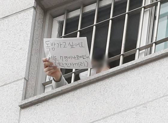 An inmate at Seoul Dongbu Detention Center in Songpa District, southern Seoul, holds a sign Sunday that reads, “I want a room to myself. Seven confirmed patients are still gathered [in a single room].” More than 1,100 coronavirus cases have been traced to the facility. [NEWS1]