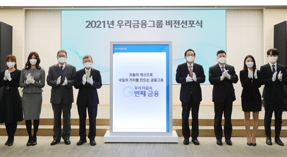 Woori Financial Group Chairman Son Tae-seung, fifth from left, Woori Bank CEO Kwon Kwang-seok, sixth from left, and related officials, including outside directors of the financial group pose for a photo to commemorate the second anniversary of the foundation of Woori Financial Holdings at the group's headquarters in Jung District, central Seoul, on Monday. Son asked related companies to strive for digital innovation, business efficiency and to bolster synergies between subsidiaries during the commemoration ceremony. [WOORI FINANCIAL GROUP] 