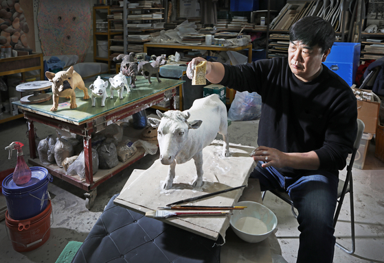 Sculptor Joo Hoo-sik works at his studio in Goyang, Gyeonggi, to recreate the image of a cow he used to play with when he was young.[PARK SANG-MOON]