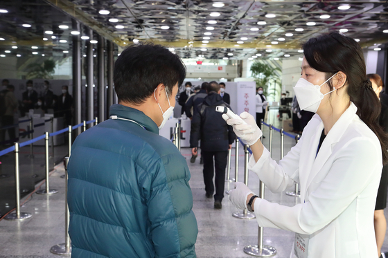 A KT worker checks participants' temperatures before entering a shareholder meeting held last year. [KT]