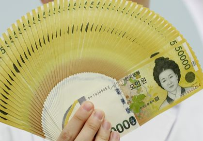 A Hana Bank employee holds up 50,000 won note in 2019. [YONHAP]