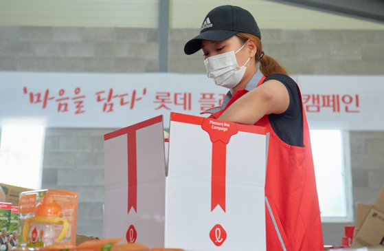 A woman packs a Lotte Pleasure Box containing various food and baby products. [LOTTE]