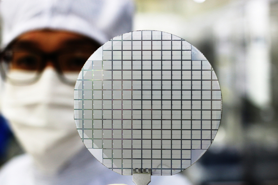 An employee at Yes Powertechnix checks a finished wafer of power chips composed of silicon carbide. [SK]