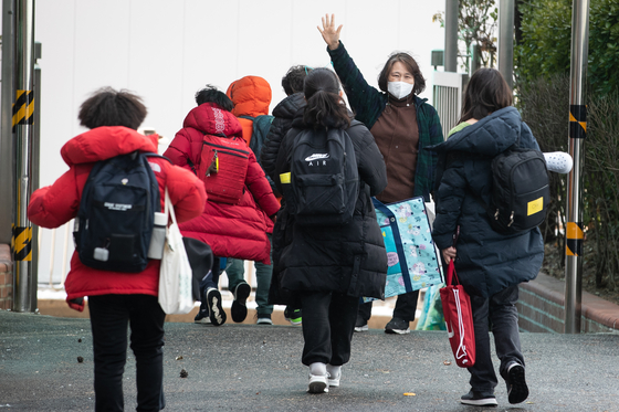 A teacher waves to her students at an elementary school in downtown Seoul Thursday. Earlier in the day, the Education Ministry announced that first and second graders will be able to go to school daily starting next semester if social distancing measures are Level 2 or lower. [NEWS1]