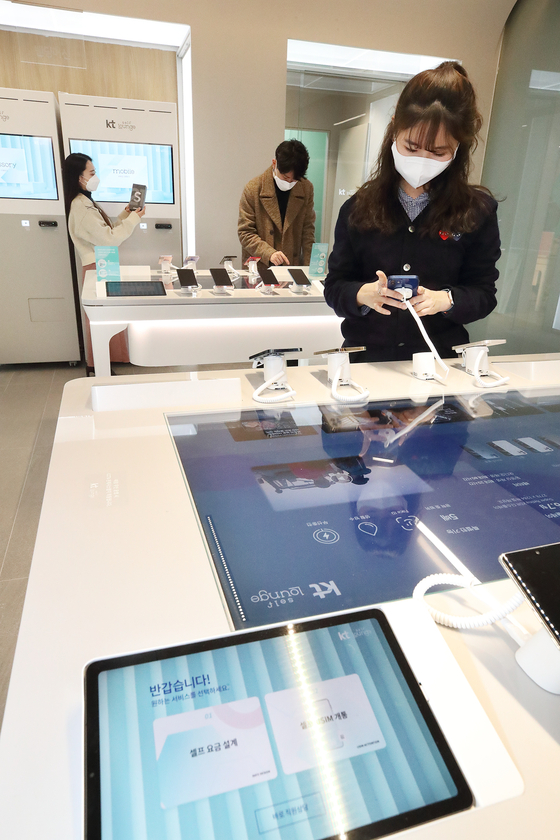 KT employees demonstrate how KT Self Lounge works in Daegu on Thursday. The telecommunications company said it has opened its first hybrid store where customers can use a kiosk by the door to tell sales clerks that they want to browse without interruption. [YONHAP]