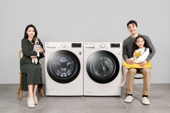 Models and a dog pose with LG Electronics’ new Tromm washer, left, and dryer that are useful for pet owners. According to the company, the washer is effective at cleaning stains from pets while the dryer is good for removing pet hair and odors. [YONHAP]