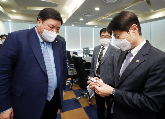 From left, Seo Jung-jin, co-founder of Celltrion, and Kim Kang-lip, head of the Ministry of Food and Drug Safety, look at a sample of CT-P59, a coronavirus treatment candidate, at a Celltrion factory in Incheon on Monday. On Feb. 5, the ministry granted conditional approval for Celltrion to market its Covid-19 treatment.[YONHAP]