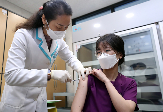 Lee Ha-yeon, 24, a nurse at an elderly care center, becomes the first person to receive a Covid-19 vaccination in Sejong on Friday. [KIM SUNG-TAE]