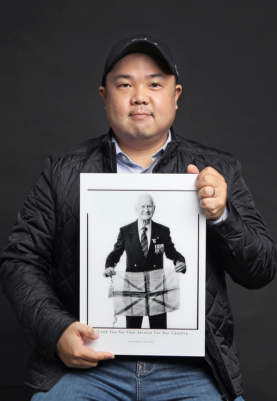 Photographer Rami Hyun, who's been taking pictures of foreign Korean War veterans since 2017, poses with one of his works — a picture of British veteran John Bowler — after an interview with the Korea JoongAng Daily at a studio in Gwanak District in southern Seoul. [PARK SANG-MOON]