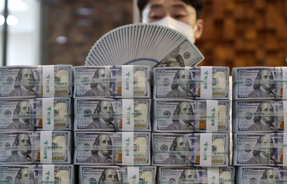 A Hana Bank employee in Myeong-dong, Seoul, counts dollars in this file photo. The BOK announced it extended a currency swap arrangement with Switzerland for five years. [YONHAP]