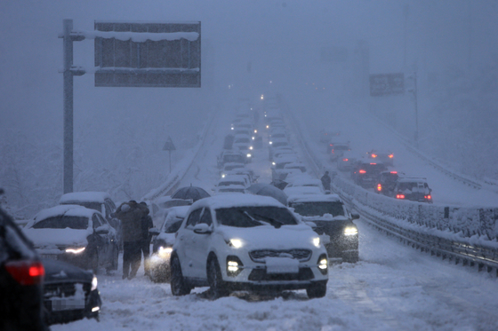 Cars are stuck on the road at Misiryeong Valley in Gangwon amid heavy snowfall Monday, the last day of a three-day weekend. [YONHAP]