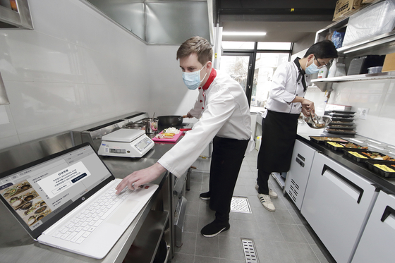 Employees at 5km Kitchen in Seodaemun District, western Seoul, use KT’s “smart green kitchen" feature, Thursday. 5km Kitchen is a shared kitchen for small food delivery businesses that can accommodate up to 31 operators. Under an agreement with its operator, Kimchi Korea, KT will provide a digital solution for the shared kitchen. According to the mobile carrier, this system provides a wide range of features, including payments, monitoring air quality inside the kitchen, energy consumption and quarantine activities of deliverymen that enter the venue. [KT]