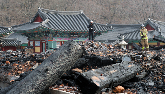 Firefighters on Saturday survey the charred remains of Daeungjeon hall at Naejang Temple in Jeongeup, North Jeolla after a disgruntled monk torched the building. [NEWS1]