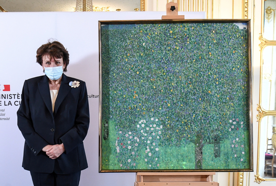 French Culture Minister Roselyne Bachelot poses next to the painting ″Rosebushes under the Trees″ by Austrian painter Gustav Klimt, during an event to announce the restitution of the artwork to a Jewish family from which it had been despoiled in 1938, at the Musee d'Orsay in Paris on Monday.  [YONHAP/REUTERS]