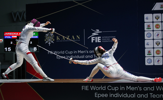 Poland's Aleksandra Jarecka, left, and Korea's Song Se-ra struggle in their gold medal bout as part of the Kazan 2021 Men's and Women's Epee Team World Cup fencing event at the Kazan Expo International Exhibition Centre in Kazan, Russia. [TASS/YONHAP]