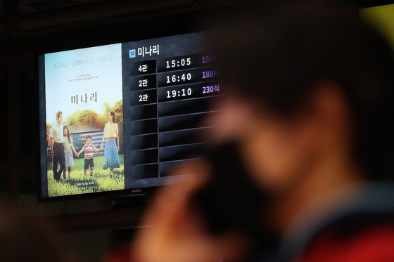 A visitor at a cinema in Seoul passes by a digital poster for ″Minari″ on March 28. [NEWS1]
