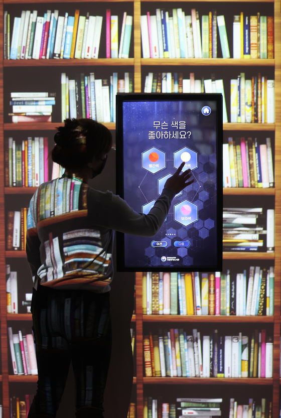 A demonstrator uses an electronic kiosk during the National Library of Korea's ″The Live Library″ exhibition, in Seocho District, southern Seoul on Monday. The kiosk recommends books to visitors based on their mood. [YONHAP] 