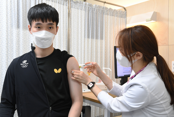 Korean table tennis player Lee Sang-su, who will compete at the Tokyo Olympics, receives a Pfizer vaccine at the National Medical Center in Seoul on Thursday, as the nation begins vaccinating athletes and coaches set to attend the Games. [YONHAP]