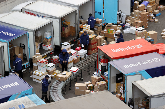 Workers categorize packages at a logistics facility in Seoul in January. [YONHAP]