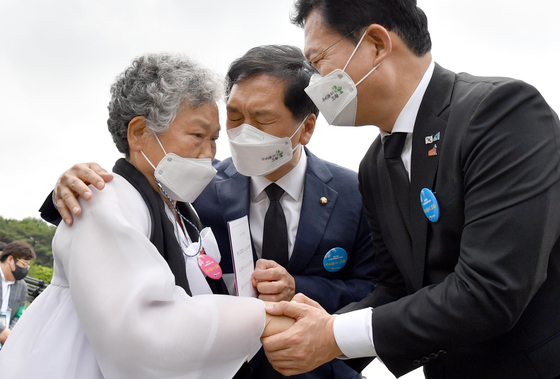 From right, ruling Democratic Party Chairman Song Young-gil and opposition People Power Party's acting Chairman Kim Gi-hyeon comfort a relative of a victim of the May 18 Gwangju Democratization Movement of 1980 at the May 18th National Cemetery in Gwangju on Tuesday. [YONHAP]