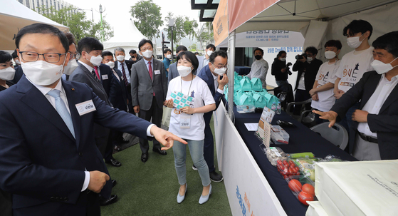KT CEO Ku Hyeon-mo, left, visits a stand in front of the KT building in Gwanghwamun, central Seoul, on Tuesday. The store is part of KT's environmental, social and governance (ESG) campaign where owners of small businesses create and sell meal kits. [YONHAP] 