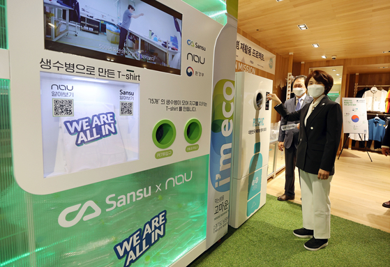 Environment Minister Han Jeoung-ae puts a plastic bottle into a crusher machine in Blackyak's Yangjae branch in Seocho District, southern Seoul, on Wednesday. The plastic bottle and T-shirt exchange event shows how plastic bottles can be recycled. [YONHAP]