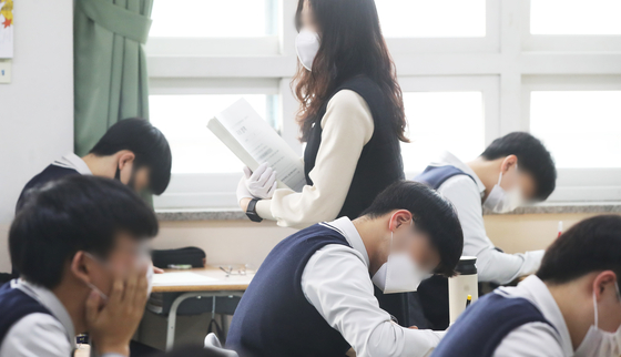 Students at Jowon high school in Suwon, Gyeonggi, take a test. Stricter restrictions were imposed during the pandemic, with students obliged to wear masks and teachers having to wear gloves during tests. [YONHAP]