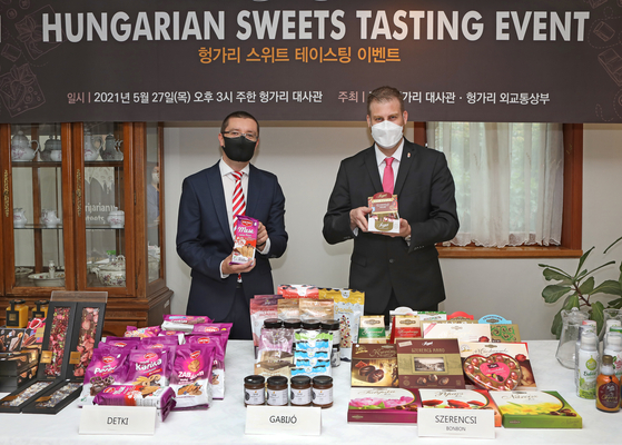 Mozes Csoma, ambassador of Hungary to Korea, right, poses for a photo with a box of chocolates during a Hungarian Sweets Tasting Event held at the Hungarian Embassy in Yongsan District, central Seoul, on Thursday. Products from a total of six Hungarian confectionery companies including chocoMe, Detki and Szerencsi Bonbon were introduced for tasting during the event as part of efforts to help Hungarian companies that wish to become export partners with the Korean market. [PARK SANG-MOON]