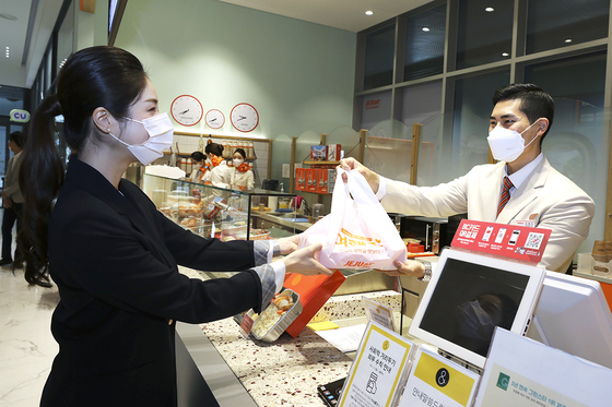 A Jeju Air flight attendant delivers an inflight meal package to a customer at its temporary offline restaurant in Hongdae, western Seoul. [JEJU AIR]