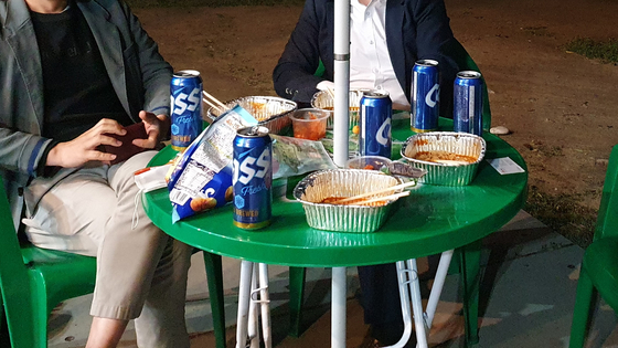  46-year-old Jung Ji-young enjoys typical Han River park food with his friends in Yeouido Han River Park on May 21 around 9 p.m. [HALEY YANG] 