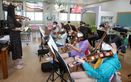 Elementary students learn how to play the violin in an after-school class at Mandeok Elementary School in Damyang, South Jeolla, on Monday. All students at 822 elementary and secondary schools in South Jeolla were required to come to school in person as the vaccination rate among its population exceeded 26 percent. [YONHAP]
