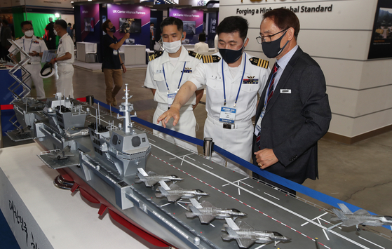 Visitors look at a miniature of a light aircraft carrier on display at the International Maritime Defense Industry Exhibition (Madex) in Busan on Wednesday. Some 120 companies from seven countries are participating in the exhibition. [NEWS1]