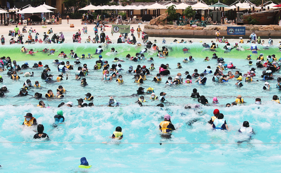 People splash and play in the water at Caribbean Bay water park in Yongin, Gyeonggi, on Sunday as the weather gets hot. [YONHAP]