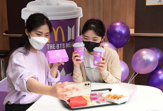 Customers pose with the BTS Meal at McDonald’s. [MCDONALD’S KOREA]