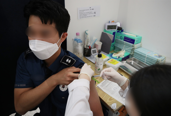 A police officer gets a Pfizer shot at a vaccination center in Yongsan District, central Seoul, on Tuesday, when inoculations began for essential personnel as well as daycare center, kindergarten, and first- and second-grade elementary school teachers under 30. [YONHAP]
