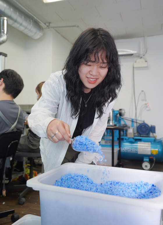 Kim Ja-yeon, project manager and one of the founders of Plastic Mill, examines ground plastic that has been divided by color and property at the mill’s office in Jung District, central Seoul. [JEON TAE-GYU]