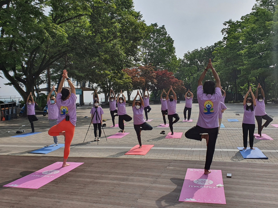 Sripriya Ranganathan, ambassador of India to Korea, center in the front row of people facing the instructors, and staff members at the embassy take part in a yoga session at Namsan Tower in central Seoul on Monday in the lead up to International Yoga Day on June 21. To celebrate the seventh year since the day was first dedicated to yoga by the United Nations, the Swami Vivekananda Cultural Centre of the Embassy of India in Seoul is organizing a number of yoga sessions in Seoul, Busan, Gimhae and other cities in partnership with local schools and universities. [EMBASSY OF INDIA TO KOREA]