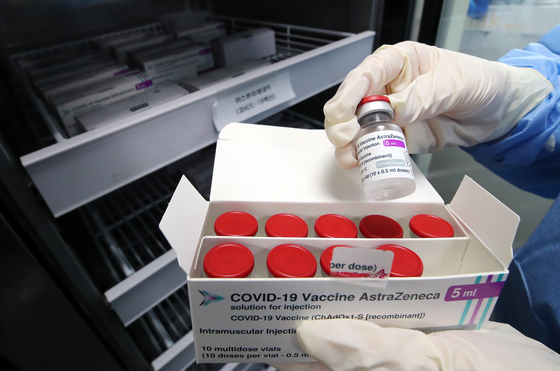 A medical professional holds a box of AstraZeneca vials. [NEWS1]