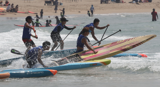 Surfers compete in the 2021 Busan Mayor’s Cup International Surfing Championship off Songjeong Beach in Busan on Sunday. Around 400 surfers competed.  [SONG BONG-GEUN]